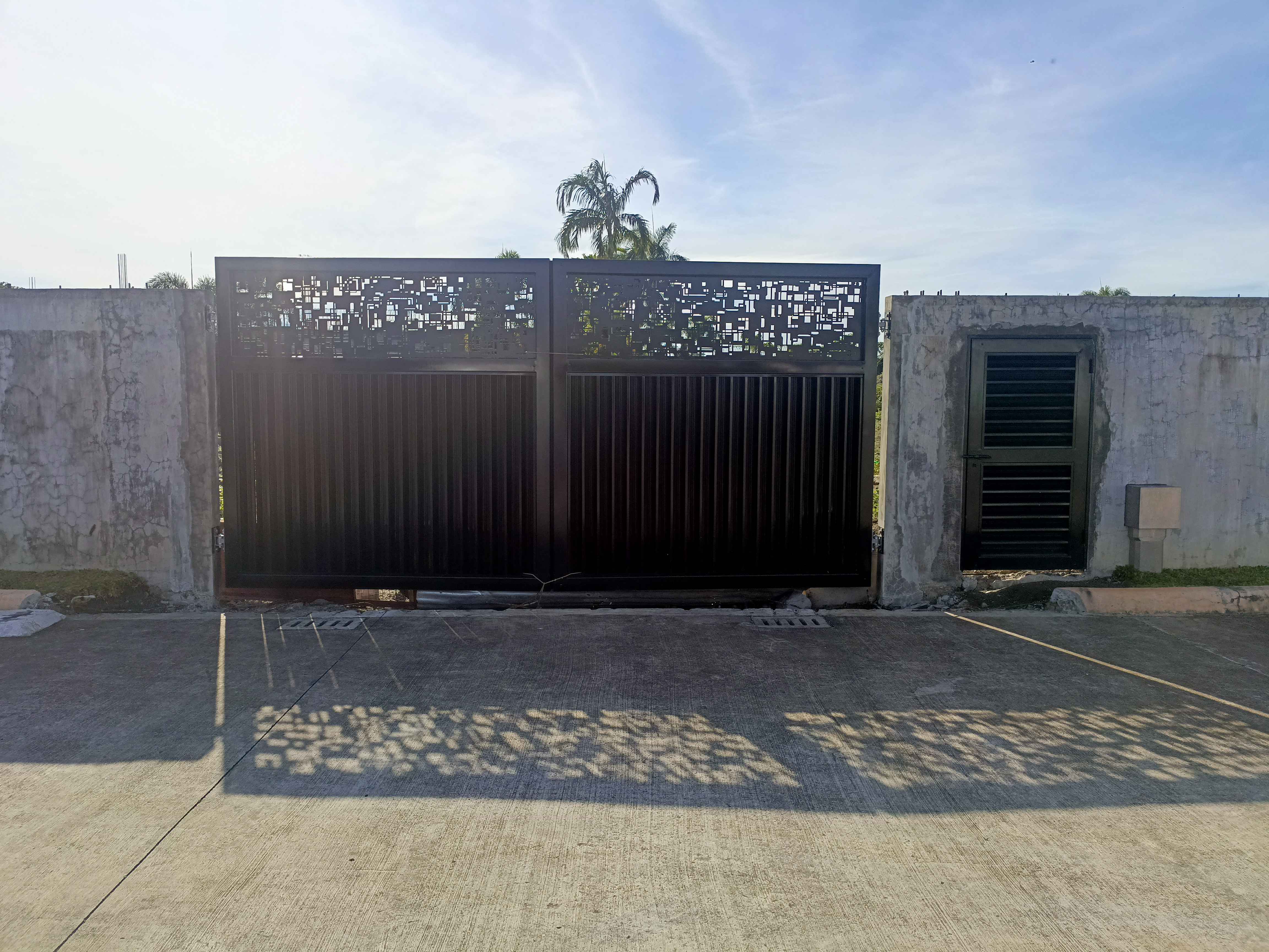 Large black driveway gate with patterned top section